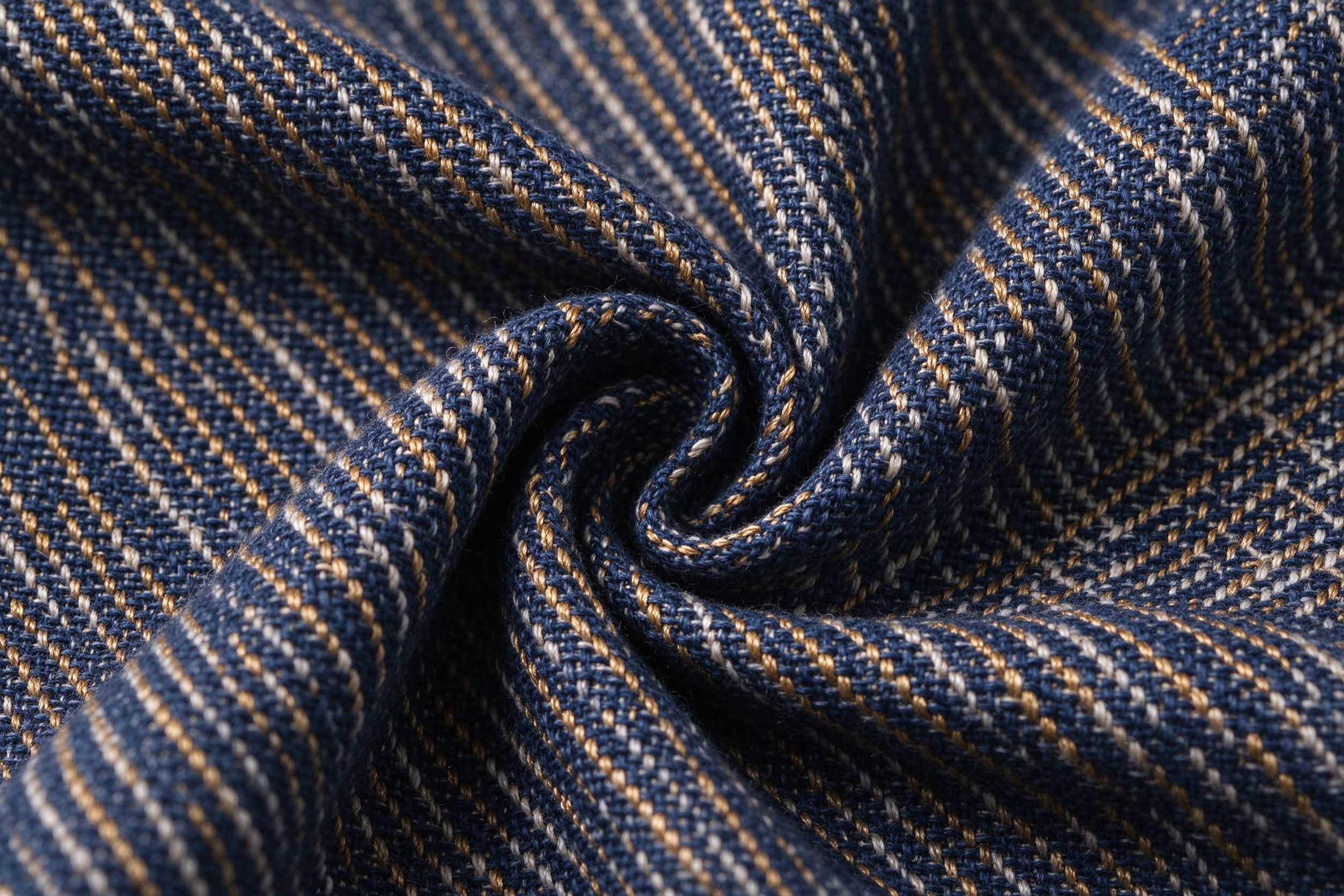 Close-up of woven navy fabric with gold and white threads